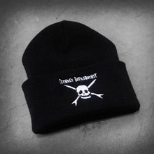 Load image into Gallery viewer, image of a black winter beanie laid flat on a concrete floor. beanie has white embroidery on the front cuff of a skull and teenage bottlerocket above it
